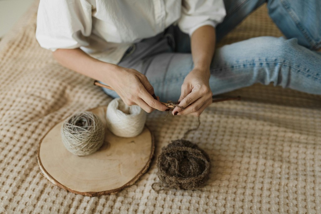 Hands knitting ribbed fabric with yarn on a wooden table