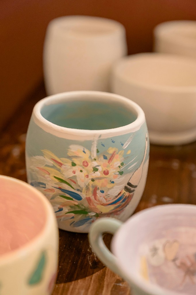 Hand painted ceramic cup among bisque pieces in the studio