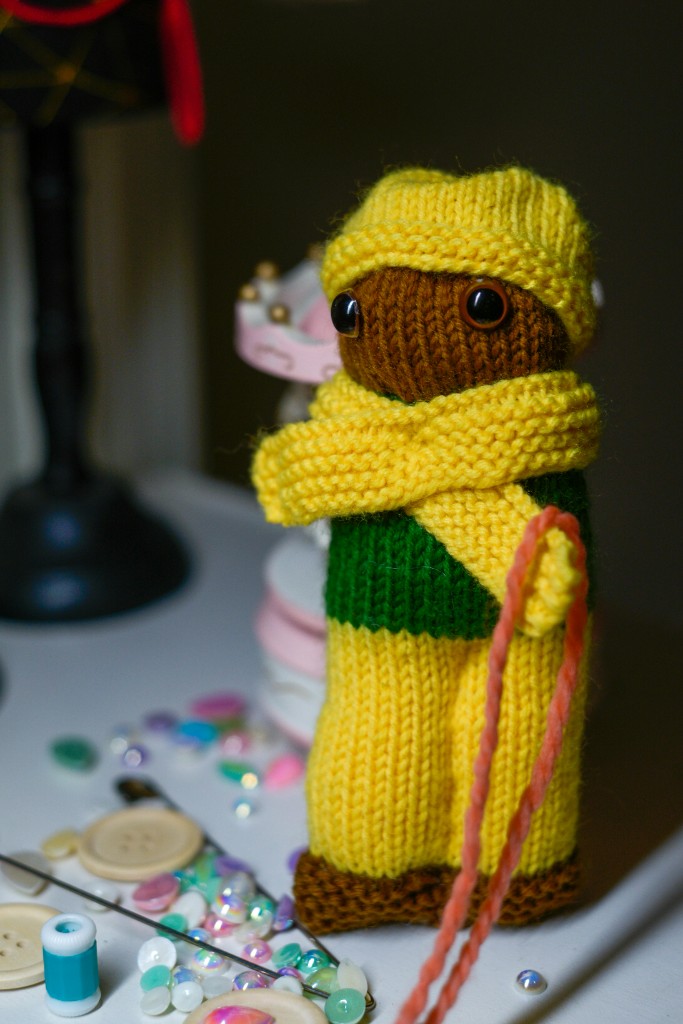 Handmade yarn doll with buttons and craft supplies on the table